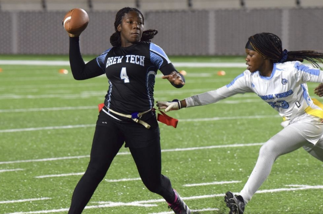 Zwei Spieler beim Flag-Football auf dem Spielfeld; eine wirft den Ball, die andere versucht die Flagge zu ziehen.
